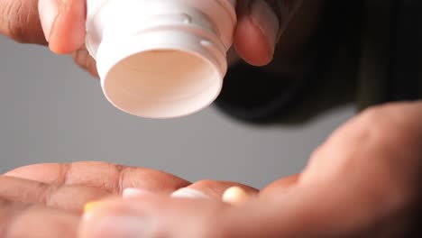 persona vertiendo pastillas de una botella en su mano