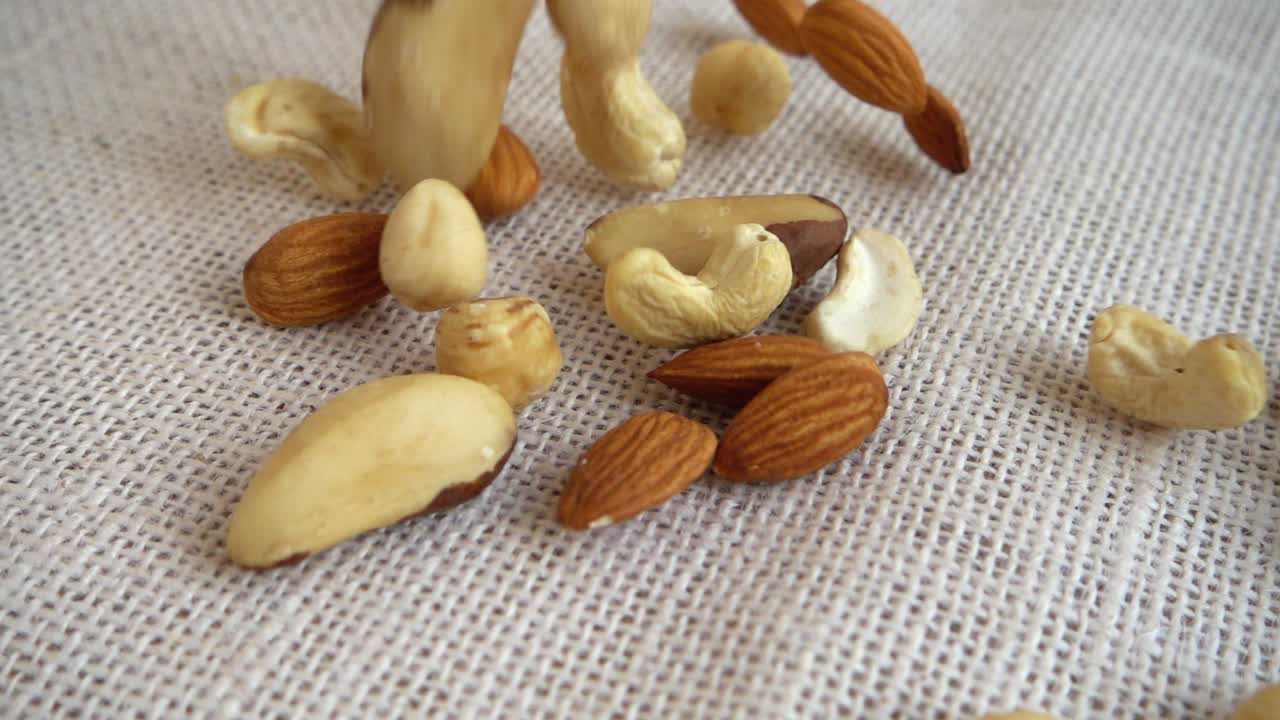 Mandler, cashewnøtter, paranøtter og hasselnøtter. Filmet mens de faller ned på en sekk. Sakte film.