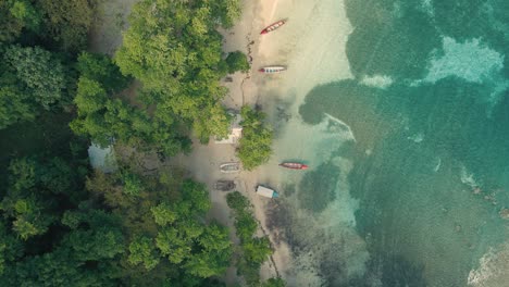 tiro de dron de playa y agua azul clara con un barco de pescadores