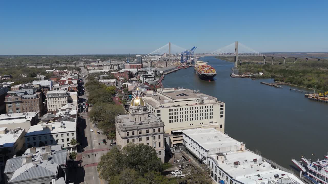 Aerial shot pulling out from Savannah City Hall and The North Historic District with a cargo ship in the background.