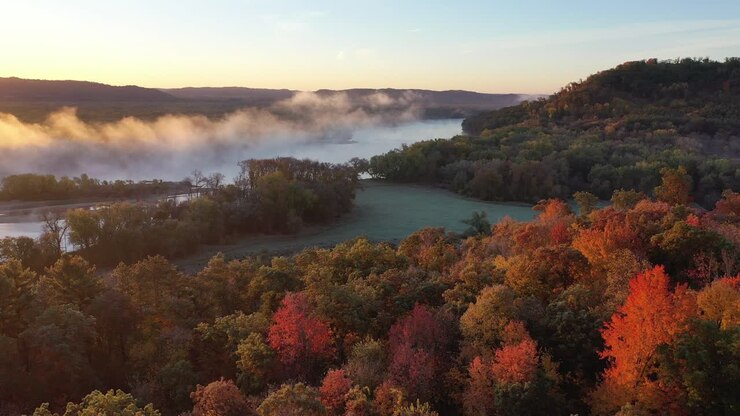 el amanecer del río brumoso sobre el follaje de otoño