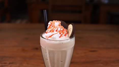 detailed close up of malted de chocomenta, with caramel, espresso and whipped cream with cherry, hand taking the cherry from the whipped cream with caramel