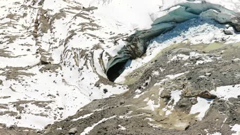 Drone reveals dark ice cave opening in Morteratsch Glacier's icy surface, Ideal for climate change, alpine exploration, Switzerland. Aerial top-down orbiting