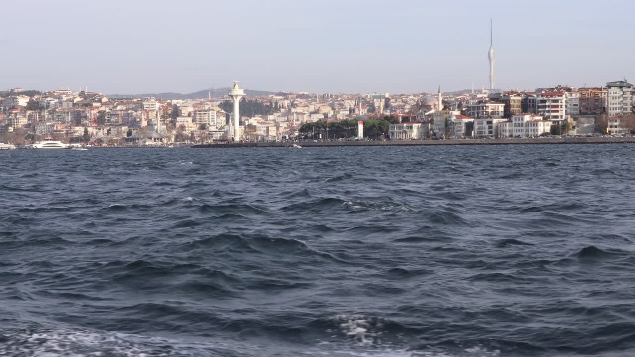 Udsigt fra en båd, der sejler på Bosporusstrædet, med bybygninger og tårne ved Üsküdar, Istanbul, Tyrkiet