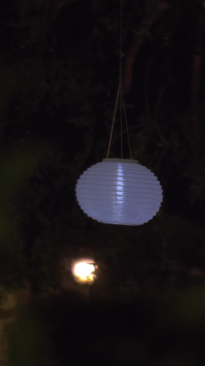 Giardino di casa con lanterne di carta bianche di notte