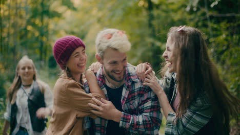 playful friends surprising young man in forest