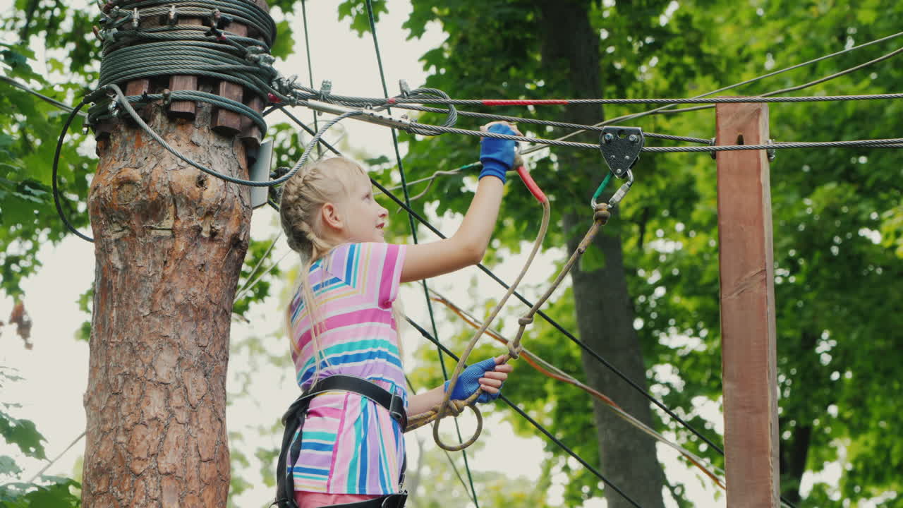 una chica valiente se mueve a lo largo de las cuerdas entre los árboles usa una cuerda de seguridad