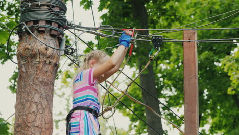 a brave girl moves along the ropes between the trees uses a safety rope