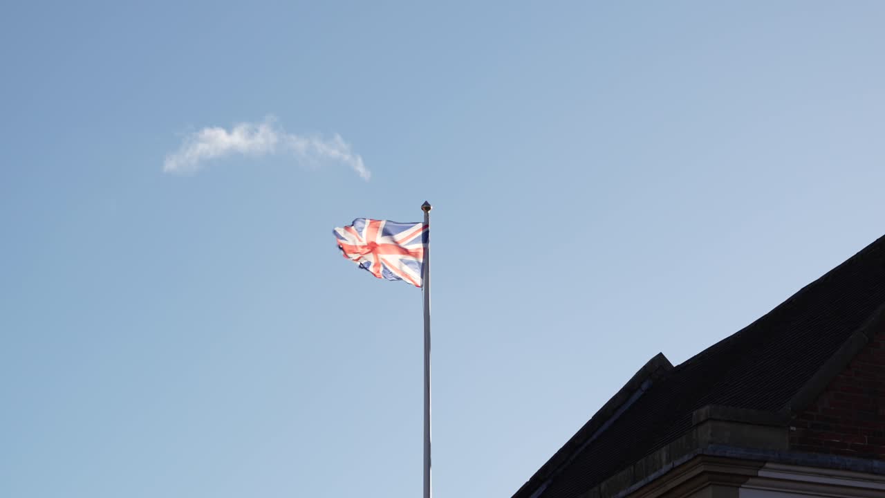 Union Jack flag waving on flagpole outdoors in British countryside town