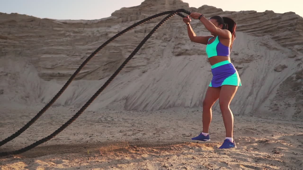 mujer atlética haciendo ejercicios de crossfit con una cuerda al aire libre.