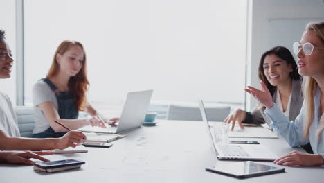 Ein-Team-Junger-Geschäftsfrauen-Mit-Laptops-Und-Tablets-Trifft-Sich-Am-Tisch-In-Einem-Modernen-Arbeitsbereich