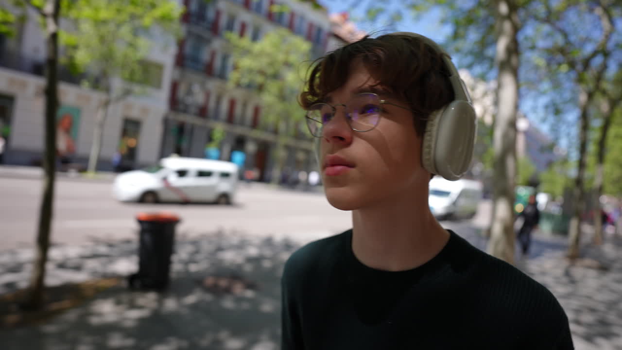 Young man shielding eyes from sun while listening to music in Madrid