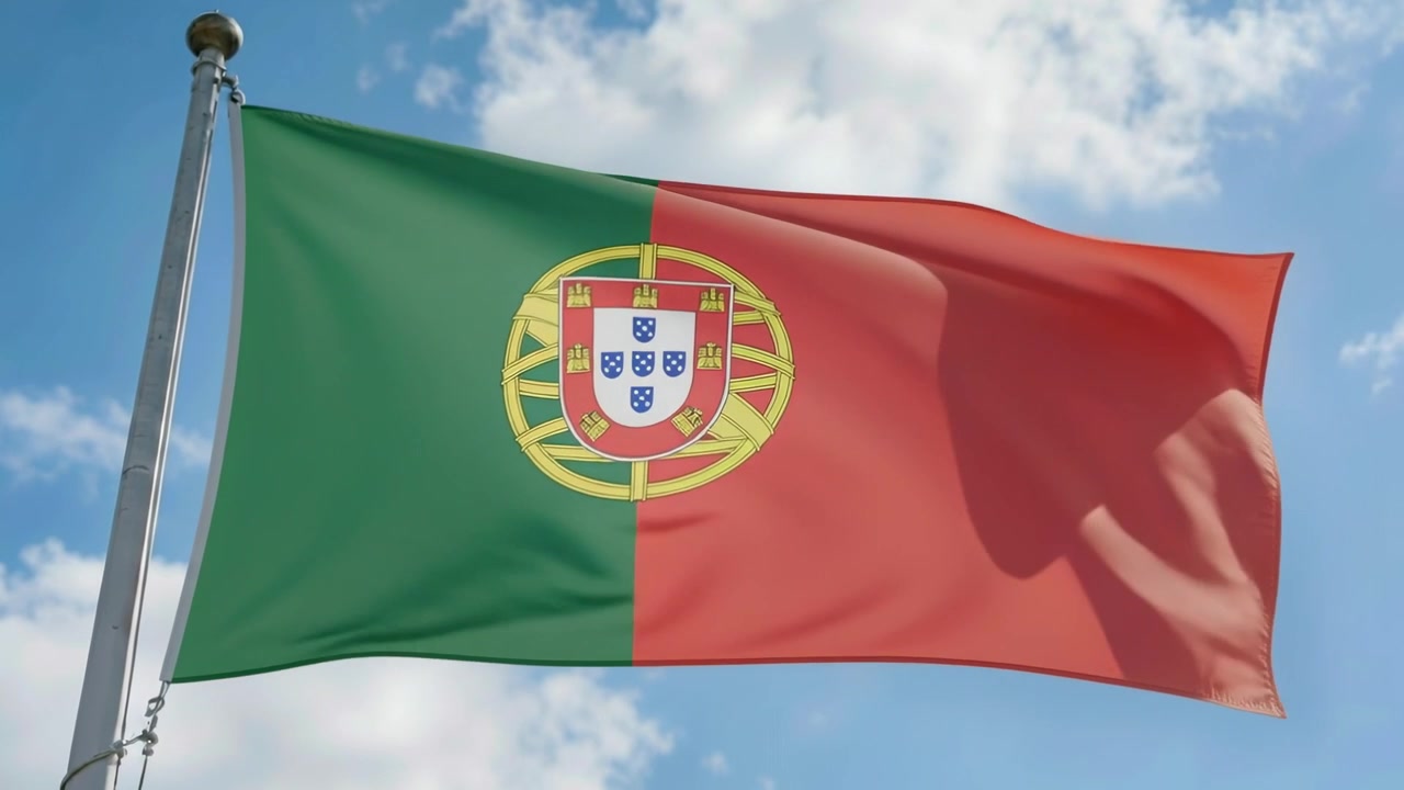 Ráfagas de viento haciendo ondear la bandera portuguesa y cambiando sus pliegues contra un cielo brillante, mástil de metal.