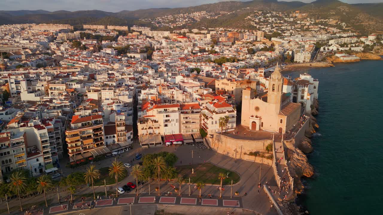 Luftfoto ved den gyldne time af kystbyen Sitges og kirke.
