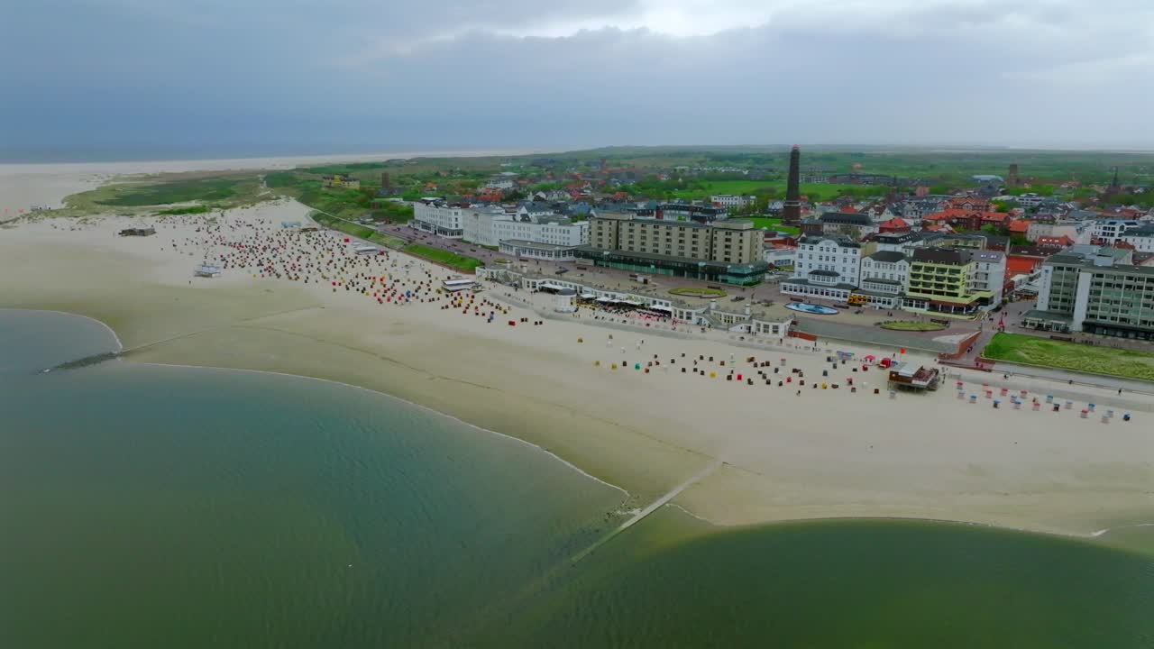 Borkum beachfront town with resort buildings and wide sandy beach. Panoramic drone aerial view