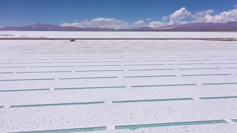 salt extraction machine working in the salt pools of the salina grande de jujuy in argentina with a mountainous volcanic landscape at the background