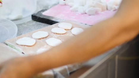 manos moldeando y aplanando la masa en tortillas