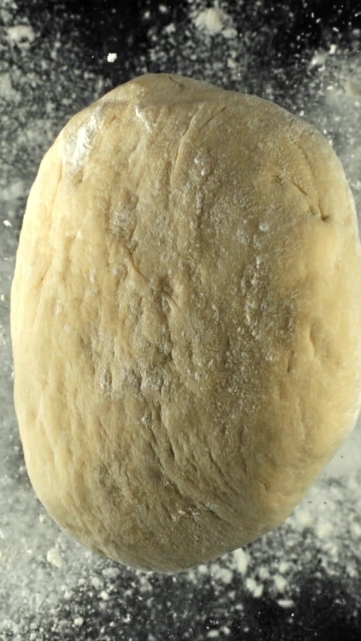 Ball of Dough Rising on Floured Black Surface