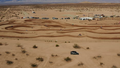 aerial view of motorcycles racing on a dirt track in mojave desert, slow motion