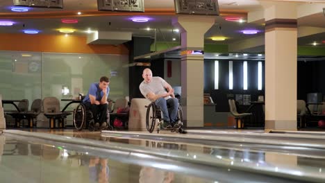 two young disabled men in wheelchairs playing bowling in the club