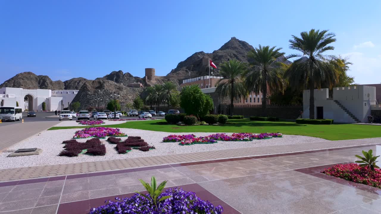 In Old Muscat, Oman looking towards the Ministry of Finance building, a flag waving, and an historic fort castle tower on the mountain
