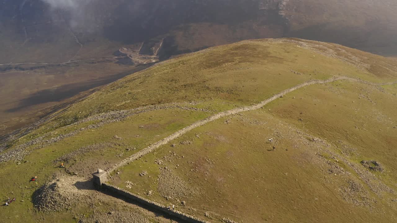 Epic top-down parallax at Slieve Donard's summit with mountaineers on the hilltop