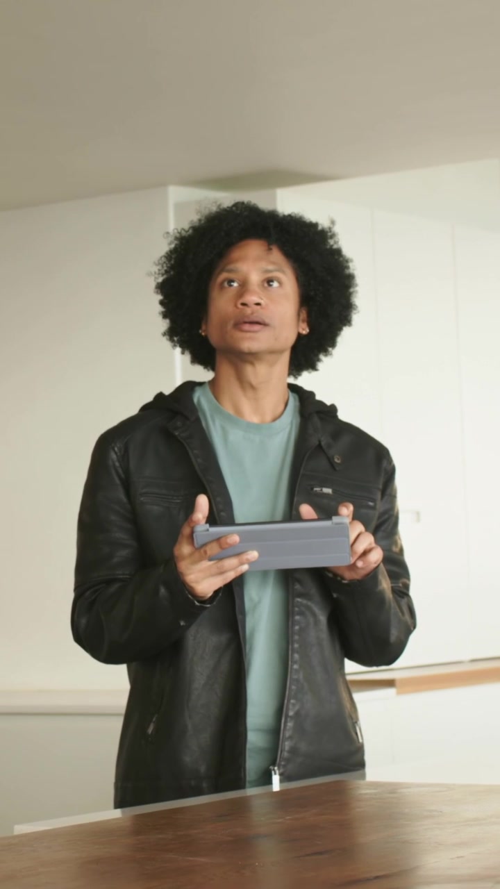 Video verticale: Uomo con camicia verde acqua che usa un tablet, controlla il soffitto come riferimento e tocca lo schermo a casa.
