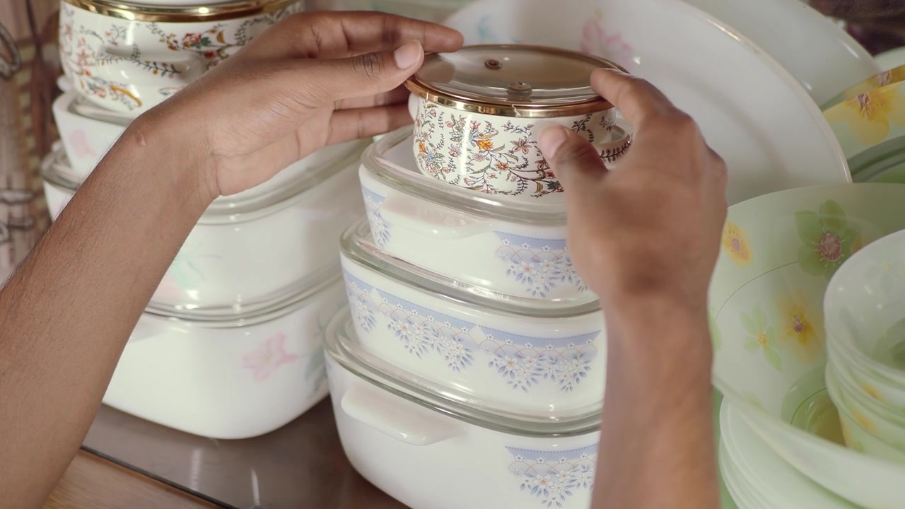 Person Picking Up a Decorative Glass Bowl from a Stack