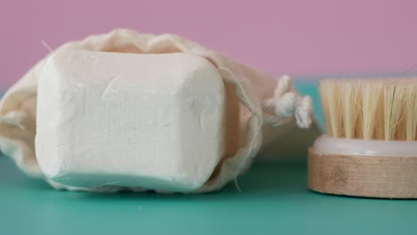 closeup of a bar of soap in a white cloth bag and a wooden brush