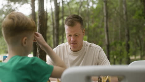 happy father and son playing chess and giving high five at the camping in the forest