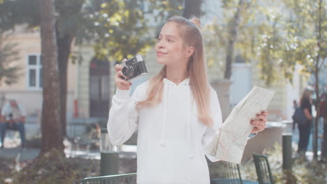 caucasian young woman tourist looking at city map making photo pictures on retro vintage camera