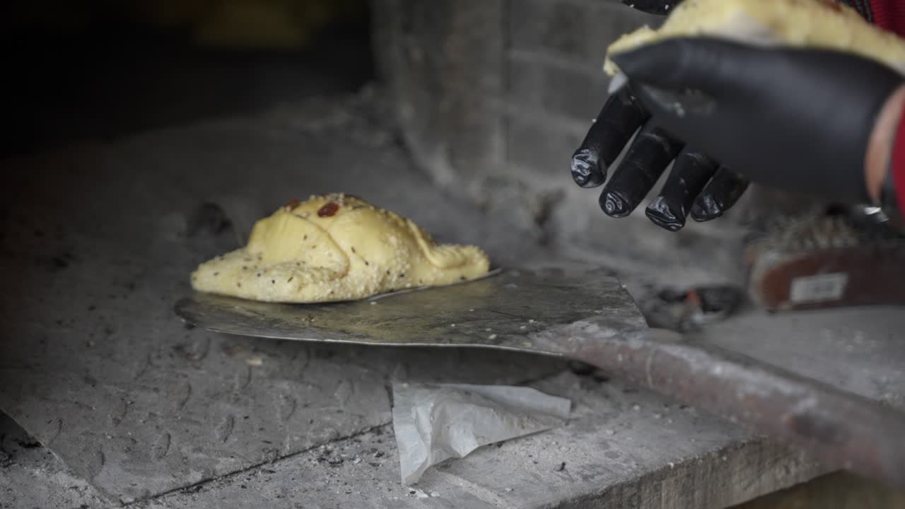 primer plano de pasteles frescos de flaouna colocados en una cáscara de metal para ser colocados dentro de un horno de piedra tradicional para hornear