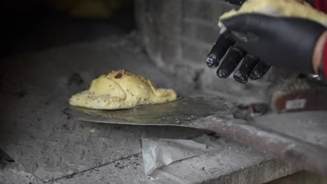 primer plano de pasteles frescos de flaouna colocados en una cáscara de metal para ser colocados dentro de un horno de piedra tradicional para hornear