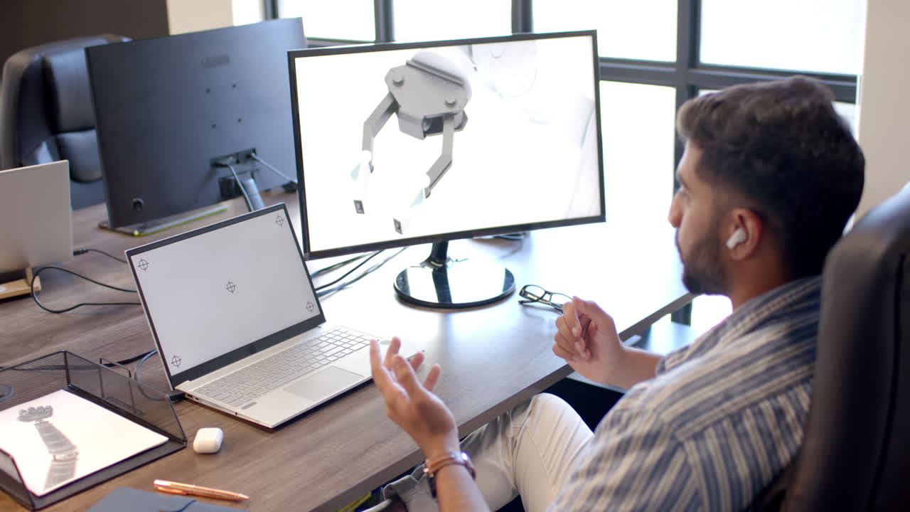 Engineer discussing robotic design, using laptop and monitor in office, copy space