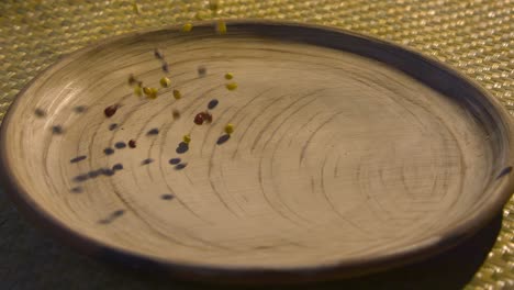 multicolored corn kernels dropped to a clay dish in slow-motion