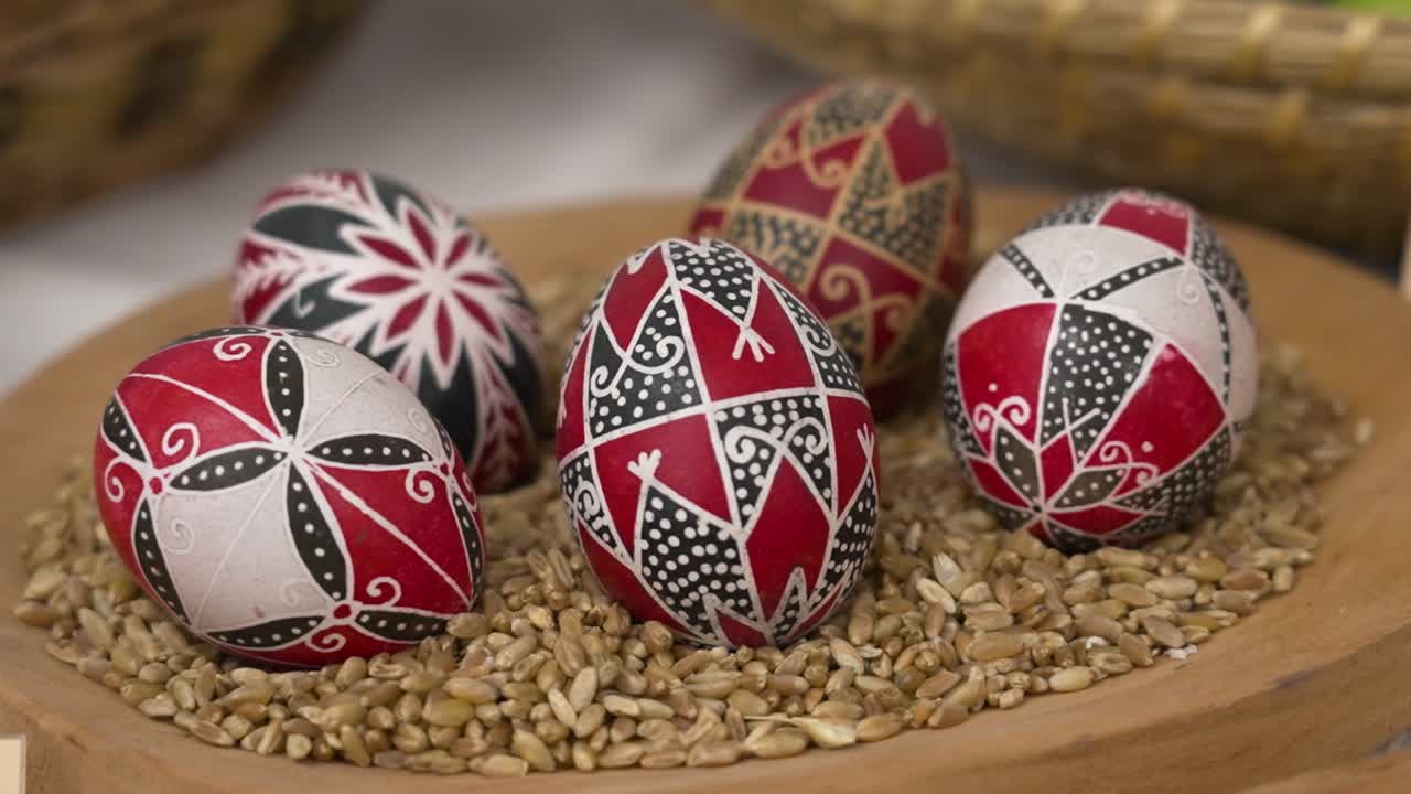 Uova di Pasqua rosso vivo e nere esposte su chicchi in una ciotola di legno