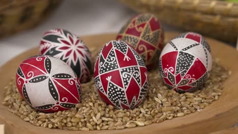 bright red and black easter eggs displayed on grains in a wooden bowl