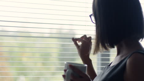 vista de cerca de una mujer de negocios en vasos bebiendo té y mirando por la ventana en la oficina