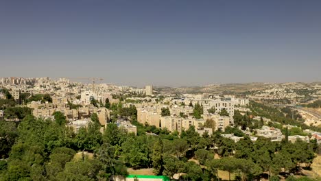 aerial fly over jerusalem suburb neighborhood at warm day,green trees growing between the buildings