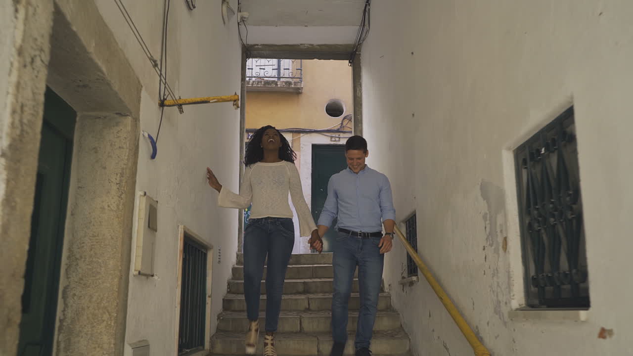 una alegre pareja multirracial bajando las escaleras.