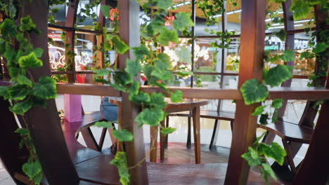 young adult seated in a decorative sit-out, focused on her phone with pink and mint green shopping bags by her side, glowing lights in background