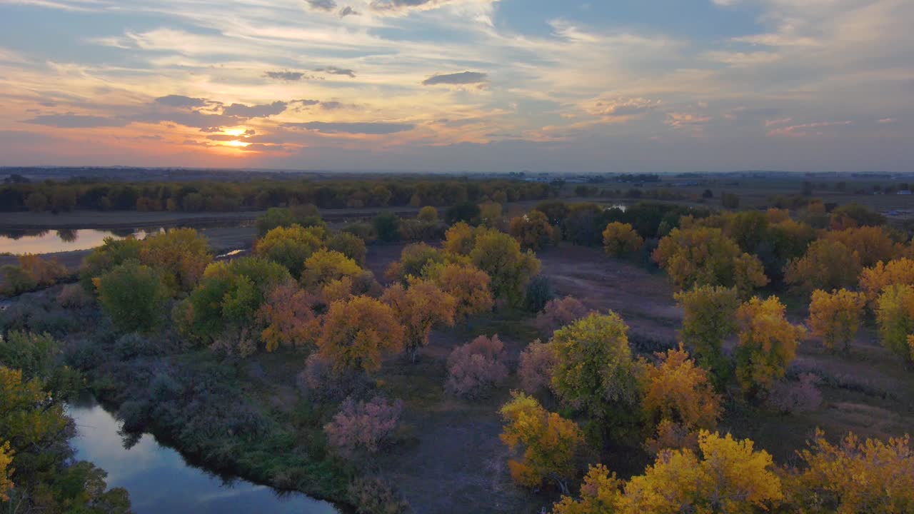Le tonalità autunnali di ambra e oro si fondono con il vivido tramonto lungo il fiume Platte nel Colorado settentrionale