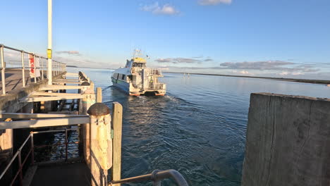 a ferry gracefully leaves the jetty, carrying passengers across calm waters under the morning sun