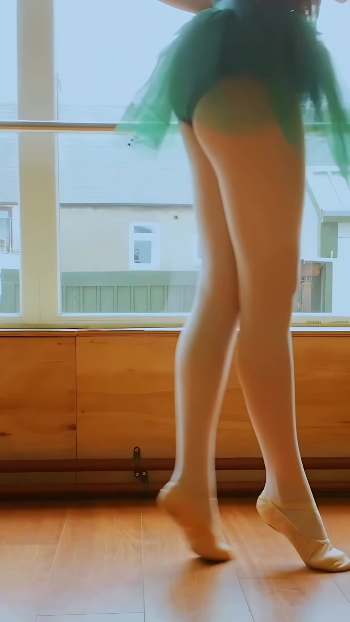 Video verticale: Iniziando a camminare, ballerina con tutù verde che pratica una sequenza di passi alla sbarra