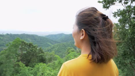 woman turns around and the camera zooms out from the left to reveal an outstretched position indicating happiness in being with nature