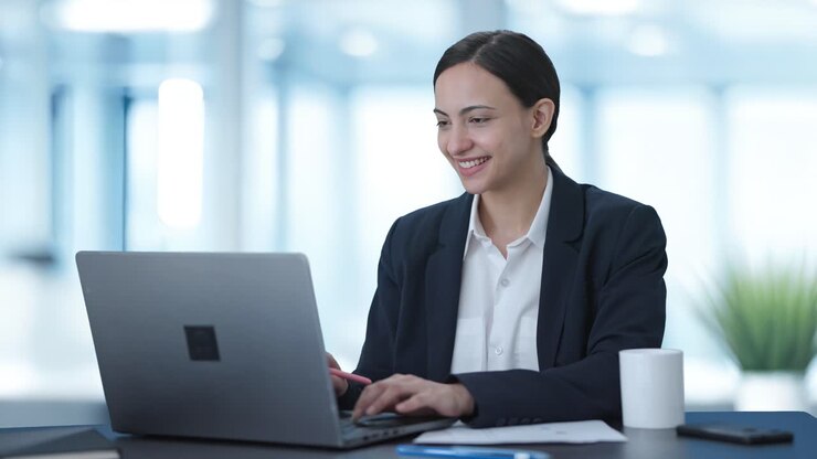 una mujer india feliz trabajando en una computadora portátil