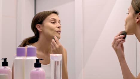 woman applying beauty product on her face in bathroom