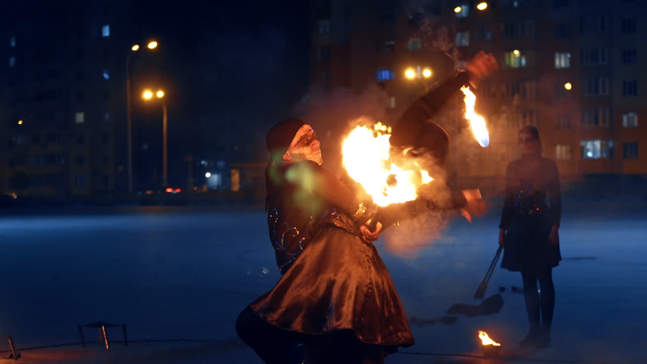 Pair of dancers perform outdoors. Man and woman dance with each other and burning objects.