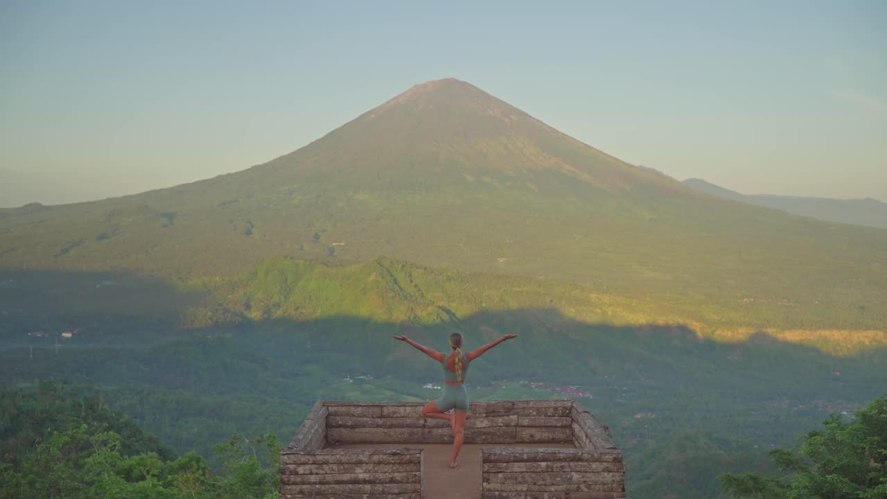 mujer en forma practicando la postura del árbol de yoga en la plataforma de madera dulce de lahangan, monte agung