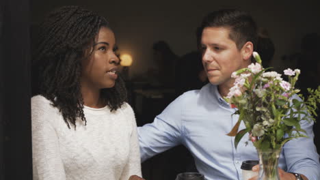 una pareja feliz sentada en una mesa en una cafetería y hablando.